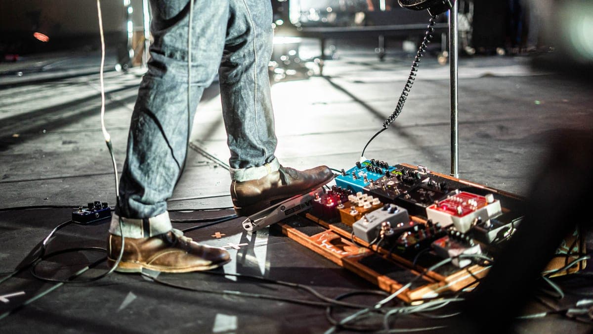 A reverb pedal glowing on a dark pedalboard