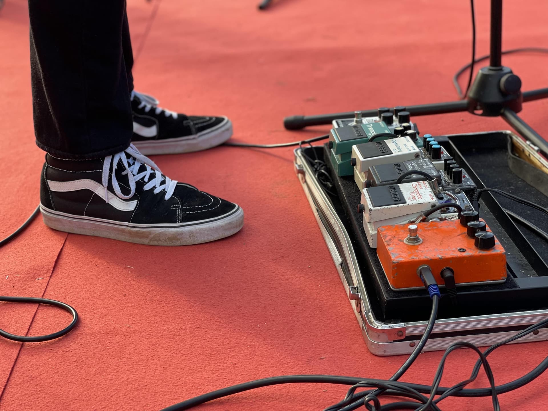 A row of guitar effects pedals wired together on a pedalboard