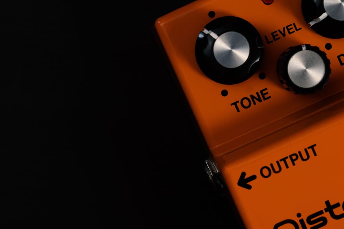 A large fuzz pedal with worn paint sitting on a stage floor