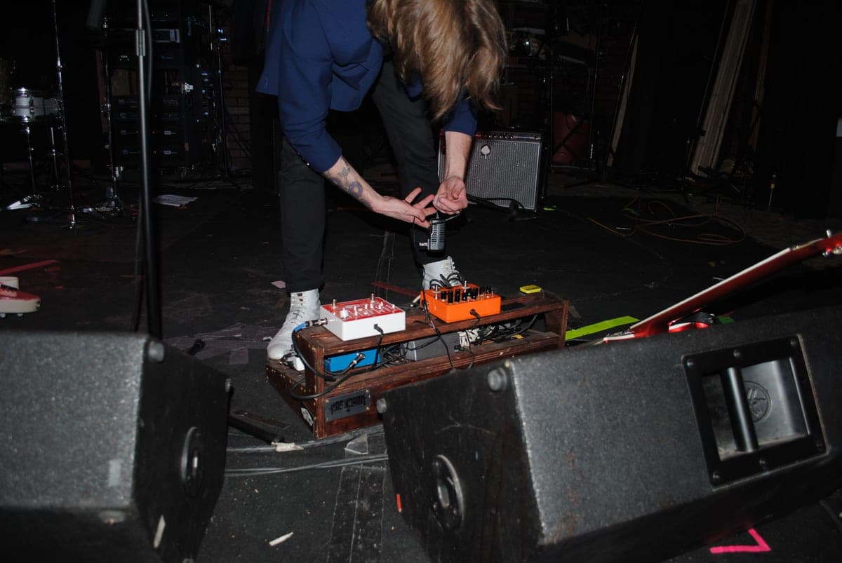 A pedalboard power supply mounted under a board with cables