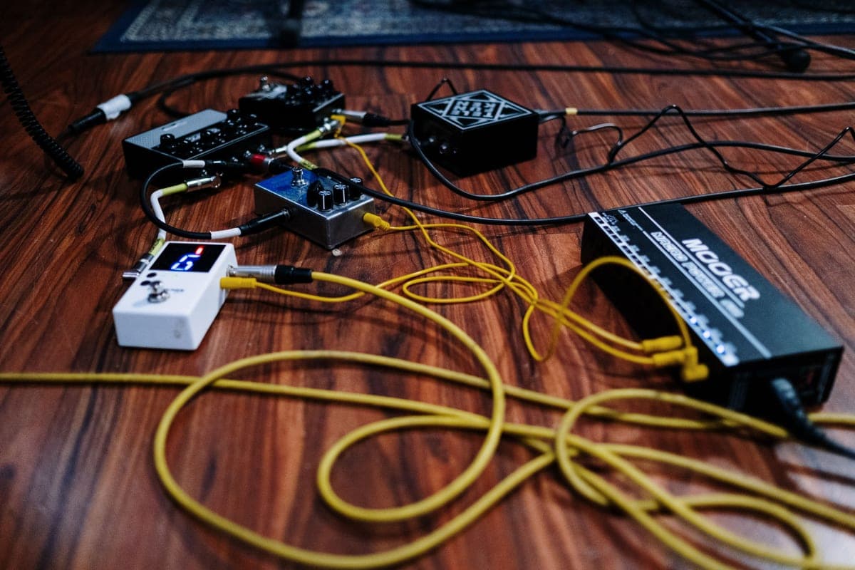 A compressor pedal on a pedalboard beside patch cables