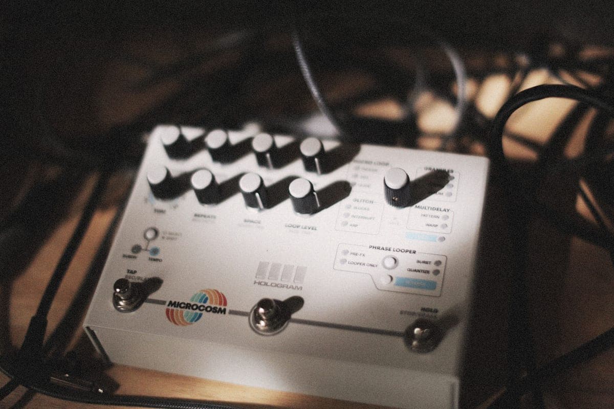 A looper pedal on a floor beside a guitar cable