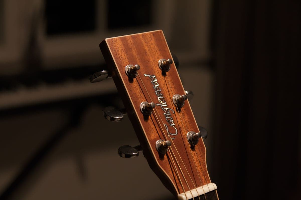A pedal tuner with a lit display on a dark board